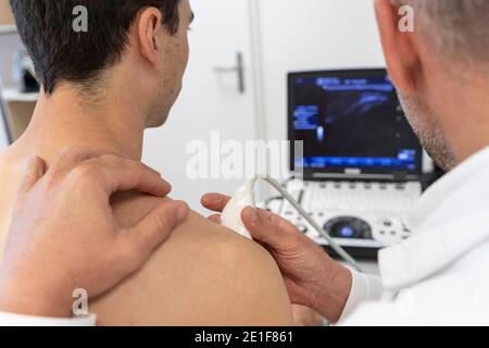 un médecin effectue une échographie sur l'épaule d'un patient Banque D'Images