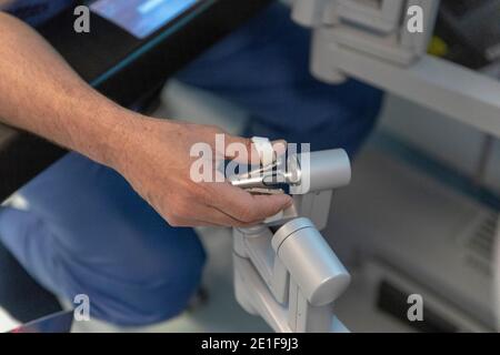 un chirurgien manipule les commandes d'un robot qui fonctionne un patient Banque D'Images