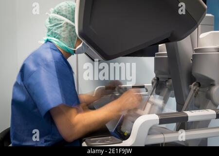 un chirurgien manipule les commandes d'un robot qui fonctionne un patient Banque D'Images