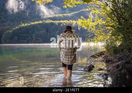 Une fille marchant pieds nus par le bord de l'eau dans un lac alpin Banque D'Images
