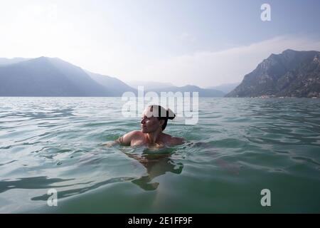 Une jeune femme flottant au milieu d'un lac En Italie Banque D'Images