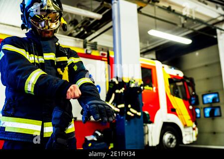 pompier mettant des gants pour se rendre en cas d'urgence Banque D'Images