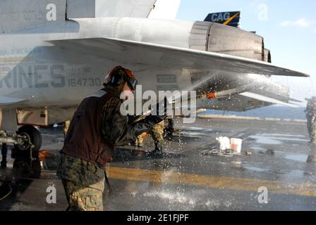 CPL lance Juan Olguin, de Lakewood, en Californie, pulvérise la surface d'un F/A-18C Hornet affecté aux chasseurs de mort de l'escadron d'attaque de chasseurs marins (VMFA) 323 à bord du porte-avions USS Ronald Reagan (CVN 76) lors d'un lavage à contre-mesure sur le pont de vol. Les marins ont frotté les surfaces externes du pont de vol et de la superstructure de l'île pour éliminer toute contamination potentielle par rayonnement. Ronald Reagan opère au large des côtes du Japon et fournit une aide humanitaire à l'appui de l'opération Tomodachi. Océan Pacifique, 23 mars 2011. Photo par NVNS via ABACAPRESS.COM Banque D'Images