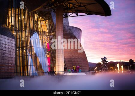 Vue extérieure de la façade incurvée en titane et en verre du musée Guggenheim à Bilbao, pays basque, Espagne au coucher du soleil. Banque D'Images