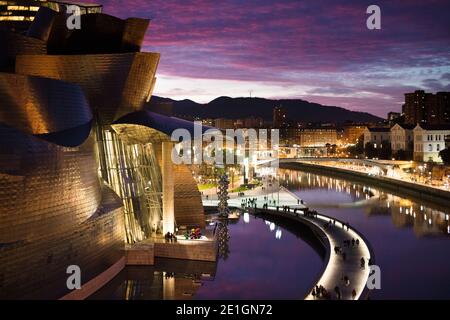 Vue extérieure de la façade incurvée en titane et en verre du musée Guggenheim à Bilbao, pays basque, Espagne au coucher du soleil. Banque D'Images