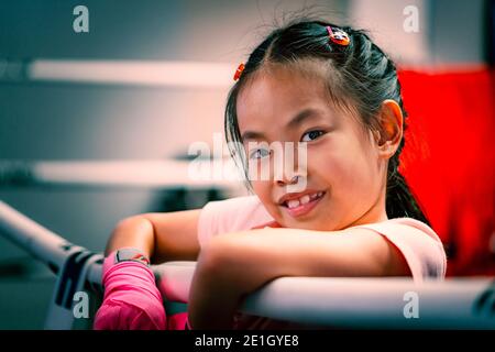 Portrait d'une fille asiatique sur l'anneau de boxe, tenant la robe de l'anneau de boxe, gros plan sur le visage mignon avec le sourire, yeux regardant l'appareil photo, couleur ajustée. Enfant Banque D'Images