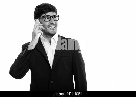 Young happy Persian businessman smiling while talking on mobile phone Banque D'Images