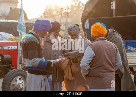 portrait d'un groupe d'agriculteurs lisant un article de presse pendant la manifestation. ils protestent contre la nouvelle loi sur les agriculteurs en inde. Banque D'Images