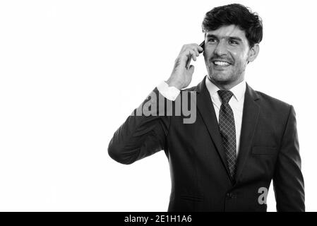 Young happy Persian businessman smiling while talking on mobile phone, portrait Banque D'Images