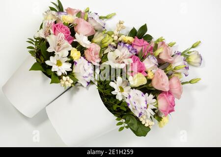 plat déposer deux bouquets de différentes tailles de roses, pâquerettes, lisianthus, chrysanthèmes, bourgeons non ouverts dans des boîtes en papier blanc sur fond blanc Banque D'Images