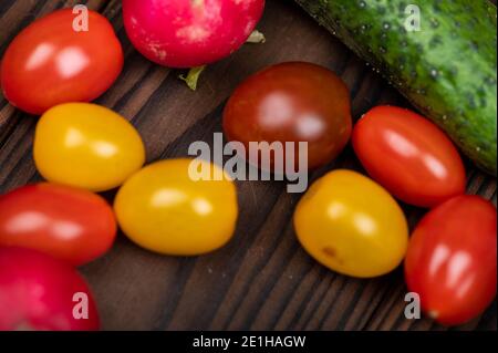 Concombres verts, radis mûrs et tomates colorées éparpillées sur la table. Gros plan, mise au point sélective Banque D'Images