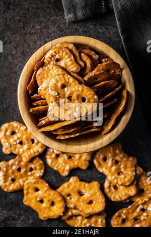 Mini bretzels plats salés dans un bol sur une table noire. Banque D'Images