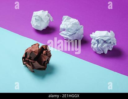 Le concept d'unicité, de discrimination raciale. Boules de papier blanc et marron froissés sur fond bleu violet. Le minimalisme Banque D'Images