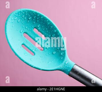 Cuillère à café en silicone, passoire en gouttes d'eau sur fond rose Banque D'Images