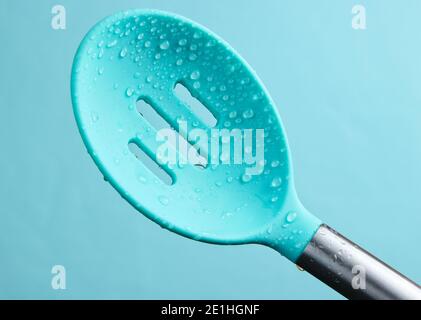 Cuillère à café en silicone, passoire en gouttes d'eau sur fond bleu Banque D'Images