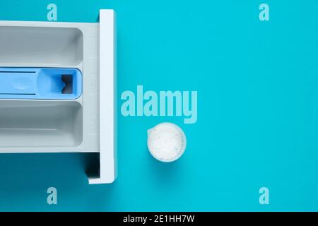 Capacité du lave-linge pour poudre, récipient de mesure avec poudre sur fond bleu. Vue de dessus, plan d'appartement Banque D'Images