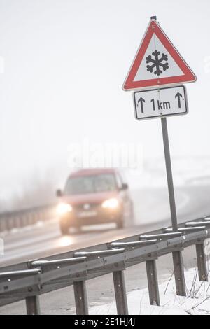 Meinerzhagen, Allemagne. 07 janvier 2021. Une voiture passe devant un panneau de signalisation indiquant qu'il y a de la neige glissante. La neige ou le grésil est tombé jeudi dans certaines parties de la Rhénanie-du-Nord-Westphalie. Credit: Marius Becker/dpa/Alay Live News Banque D'Images