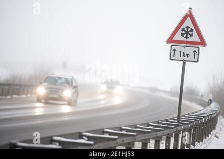 Meinerzhagen, Allemagne. 07 janvier 2021. Les voitures dépassent un panneau de signalisation indiquant qu'il y a de la neige glissante. La neige ou le grésil est tombé jeudi dans certaines parties de la Rhénanie-du-Nord-Westphalie. Credit: Marius Becker/dpa/Alay Live News Banque D'Images