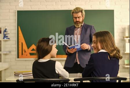 La vie scolaire quotidienne. Des amis étudient ensemble. Retour à l'école. Aide et assistance. Enseignant de niveau élémentaire. Groupe de discussion des enfants et des enseignants. Enseignant et enfants en classe. Dialogue et communication. Banque D'Images