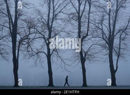 Leicester, Leicestershire, Royaume-Uni. 7 janvier 2021. Météo au Royaume-Uni. Un homme marche à travers un parc Victoria brumeux pendant le troisième confinement national du coronavirus. Credit Darren Staples/Alay Live News. Banque D'Images