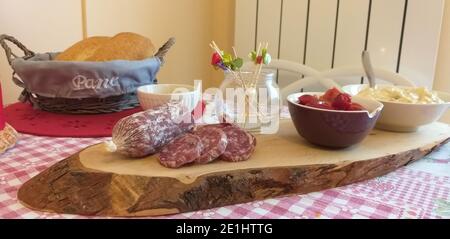 Planche à découper en bois avec hors-d'œuvre frais, salami, salade russe et poivrons grillés. Banque D'Images