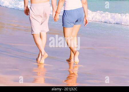 Couple tenant les mains est de marcher le long de la plage de sable de mer. Vue de dessous arrière Banque D'Images