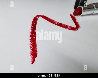 Frottis de rouge à lèvres éclatant avec de minuscules particules de microplastique sur un fond en bois blanc Banque D'Images