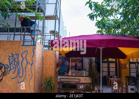 Nicosie, Chypre - 9 décembre 2020 : un homme portant un chapeau saute sur l'échafaudage à côté du café-restaurant de bus dans la vieille ville de Nicosie. Banque D'Images