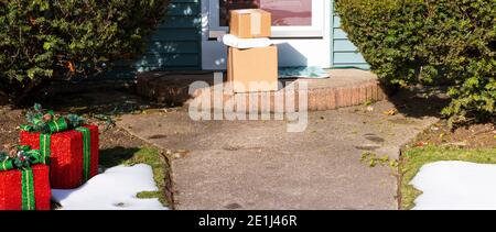 Neige sur le sol à côté des décorations des fêtes de Noël avec des paquets livrés au stoop avant. Banque D'Images