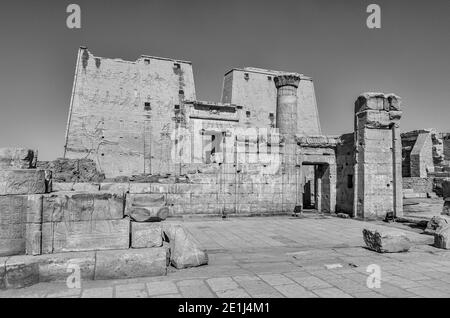 Edfu. Ce sont les pylônes d'entrée du temple 200BC d'Horus le Dieu faucon, situé à mi-chemin entre Louxor et Assouan sur le Nil et la ville d'Edfu célèbre pour ses énormes pylônes, ses colonnes finement décorées, les hiéroglyphes de cartouche racontant des panneaux muraux, et les œuvres d'art sur ses plafonds. Le temple a eu la chance que la majorité de celui-ci ait été couvert de sable soufflé par le vent préservant ainsi le temple des éléments pendant des siècles. Banque D'Images