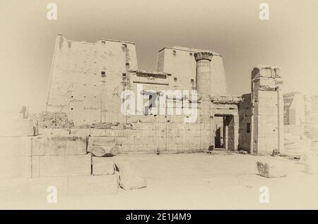 Edfu. Ce sont les pylônes d'entrée du temple 200BC d'Horus le Dieu faucon, situé à mi-chemin entre Louxor et Assouan sur le Nil et la ville d'Edfu célèbre pour ses énormes pylônes, ses colonnes finement décorées, les hiéroglyphes de cartouche racontant des panneaux muraux, et les œuvres d'art sur ses plafonds. Le temple a eu la chance que la majorité de celui-ci ait été couvert de sable soufflé par le vent préservant ainsi le temple des éléments pendant des siècles. Banque D'Images