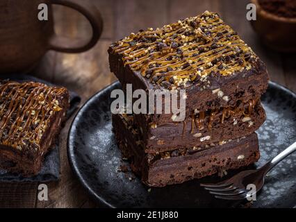 Brownie au caramel au chocolat noir avec garniture au caramel et aux noix empilées sur une plaque noire Banque D'Images