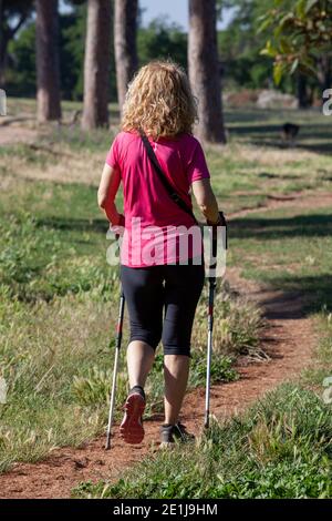 Femme faisant de la marche nordique dans le parc Banque D'Images