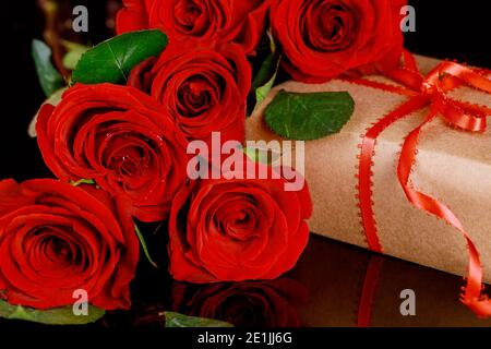 Boîte cadeau avec ruban rouge et bouquet de belles roses rouges. Concept de la Fête des mères. Banque D'Images