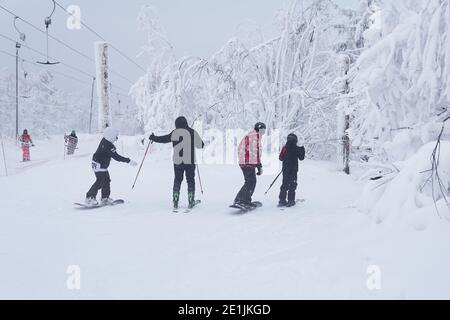 Perm Krai, Russie - le 02 janvier 2021 : les skieurs et les surfeurs des neiges adolescents vont glisser le long d'une montagne le long d'un sentier forestier par temps gelé Banque D'Images