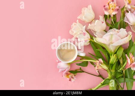 Vue de dessus d'une tasse de café frais et assortiment tendre fleurs disposées sur fond rose en studio Banque D'Images