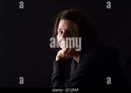 portrait d'une femme souriante avec la main sur le menton et la pensée sur fond noir Banque D'Images