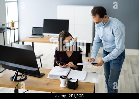 Formation de l'assistant employé portant un masque facial au bureau Banque D'Images