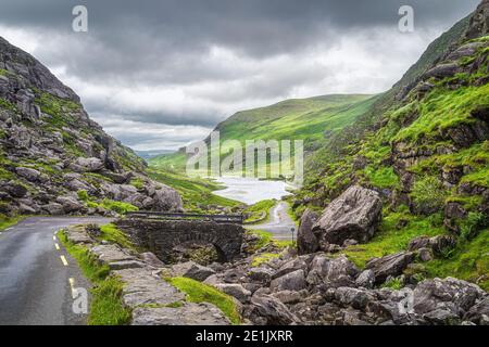 Route sinueuse étroite et pont en pierre avec vue sur Gap of Dunloe Valley et lac dans Black Valley, Ring of Kerry, comté de Kerry, Irlande Banque D'Images