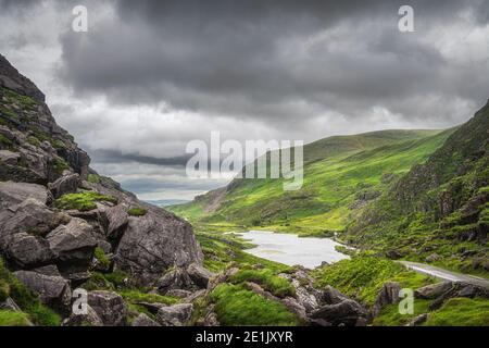 Vue panoramique sur les collines verdoyantes et un lac à Gap of Dunloe. Ciel orageux spectaculaire dans la vallée noire, l'anneau de Kerry, comté de Kerry, Irlande Banque D'Images