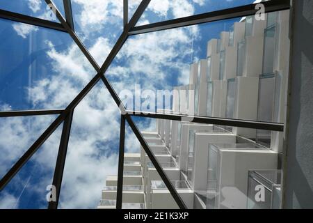 Vue à travers un ciel bleu ciel nuageux et les balcons d'un bâtiment blanc et moderne Banque D'Images