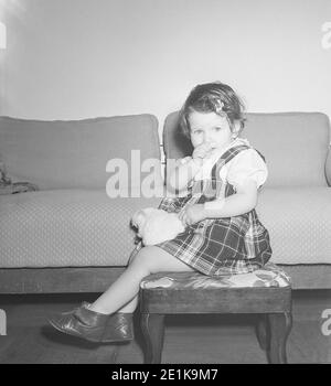 Vintage années 1950 style de vie, deux ans Old Girl pose pour caméra dans son pull à carreaux, États-Unis Banque D'Images