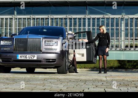 Une femme avec chauffeur ouvre la porte de la voiture pour les clients vip Banque D'Images