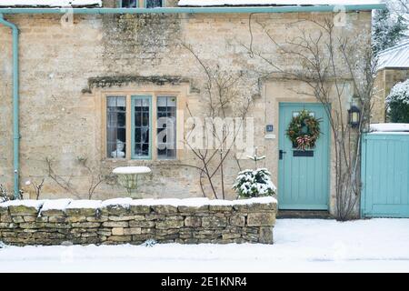 Cotswold cottage en pierre avec couronne de noël dans la neige de décembre. Taynton, Cotswolds, Oxfordshire, Angleterre Banque D'Images
