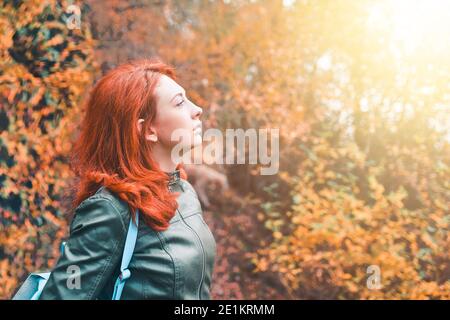 Jeune femme sur le fond d'une forêt d'automne. Portrait d'une femme aux cheveux rouges au soleil. Un voyage dans la nature. Montagnes d'automne. Veste tendance pour femme. Banque D'Images