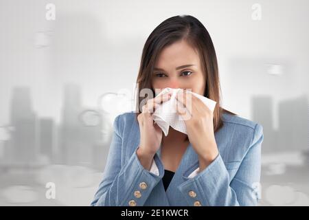 Femme d'affaires sensation de brûlure du nez en raison de la fumée toxique et des particules dans l'air. Femme allergique, tenant un tissu sur son nez. P Banque D'Images