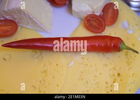 Savoureux plateau de fromages avec trois fromages assortis et frais entiers piment sur la tomate hachée en gros plan Banque D'Images