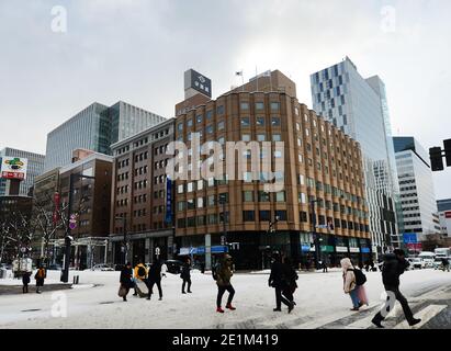 Piétons traversant une route enneigée dans le centre de Sapporo, Japon. Banque D'Images