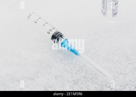 Gros plan d'une seringue médicale placée sur de la glace, représentant la vaccination, les conditions d'entreposage au froid et les soins de santé dans des environnements à température contrôlée Banque D'Images