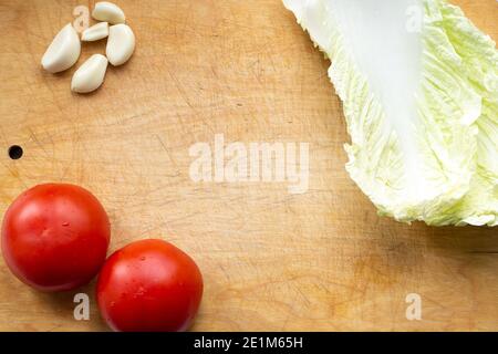 légumes sur une planche à découper, tomates, chou et ail pour une salade de printemps végétarienne, nourriture saine et savoureuse Banque D'Images